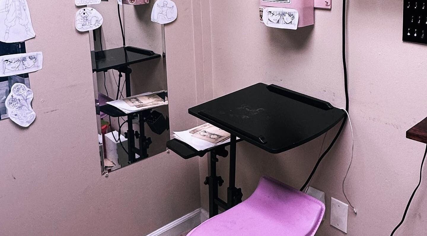 Compact tattoo workspace at K. Tabone Tattoo, Rochester, New York, US, featuring drawings and tools.