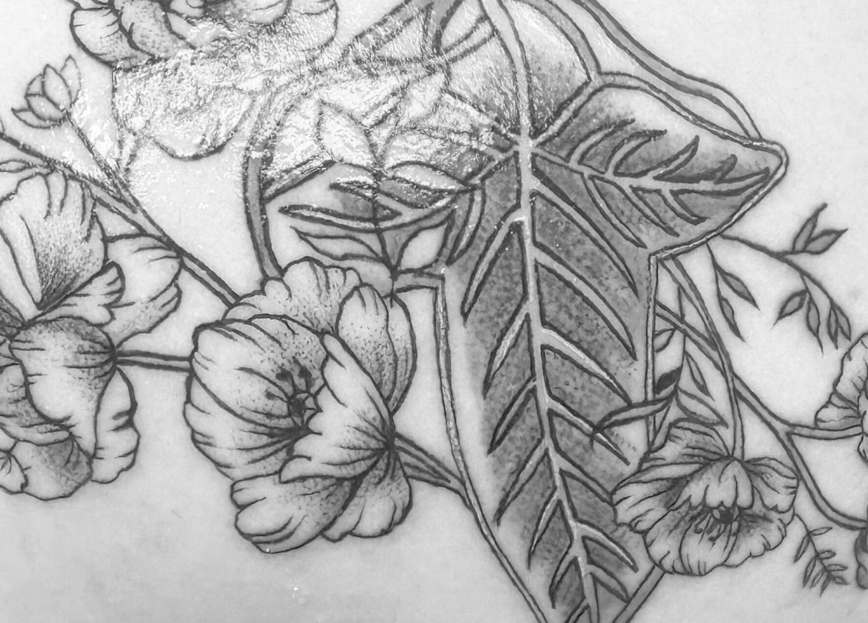 Exquisite floral tattoo art at K. Tabone Tattoo, Rochester, New York, US, showcasing intricate leaf and flower design.