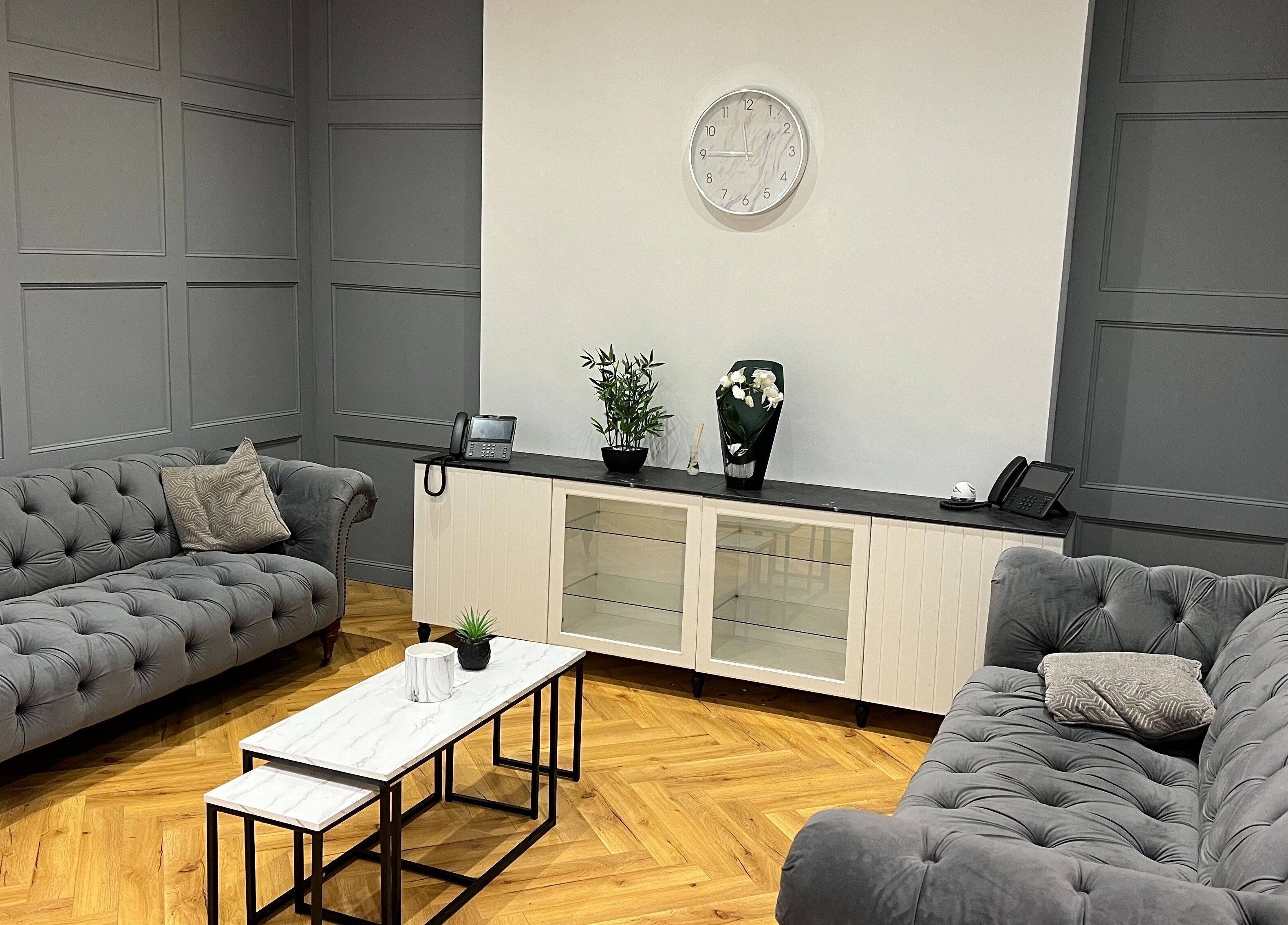 Elegant seating area at Vivo Body Studio Belfast, showcasing plush grey sofas and stylish decor in Belfast, Northern Ireland, GB.
