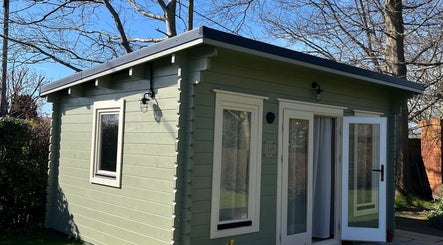 Charming cabin exterior at Beauty By Eloise, Godshill, England, GB, surrounded by trees.