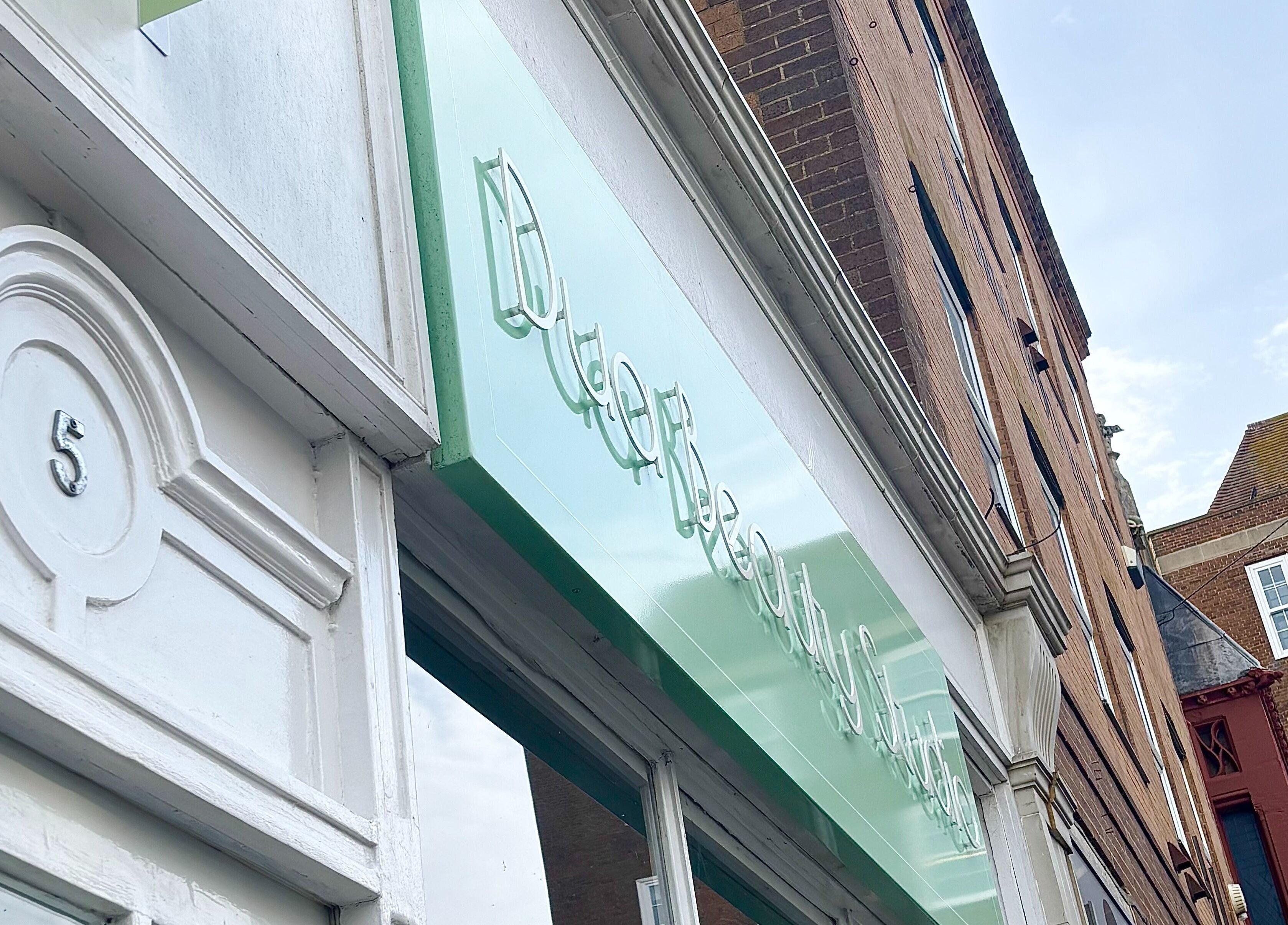 Exterior of Dua Beauty Studio in Brighton, England, GB showcasing modern signage and architecture.