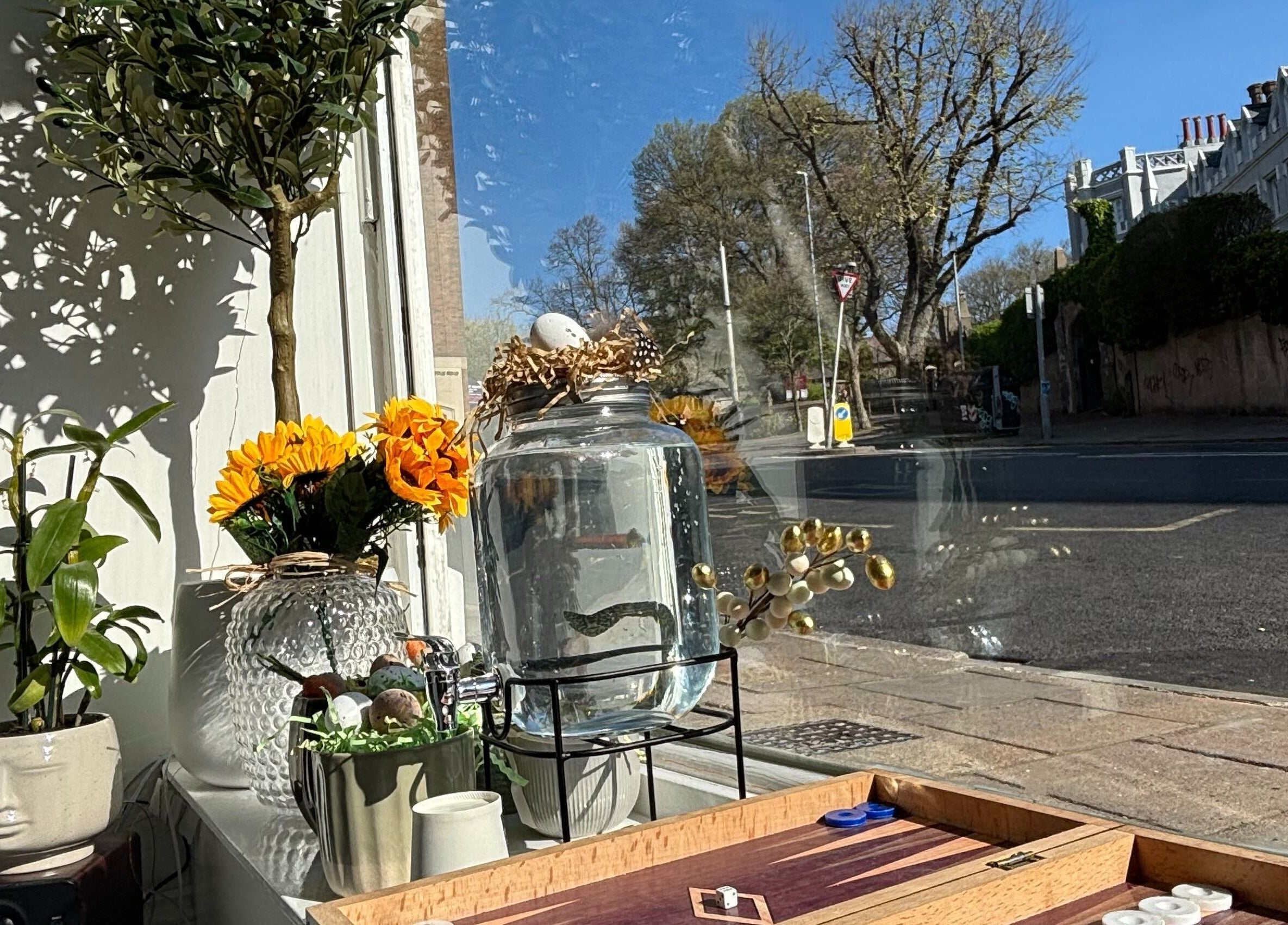 Chic decor in Dua Beauty Studio window, Brighton, England, GB, featuring plants and a large water jar.