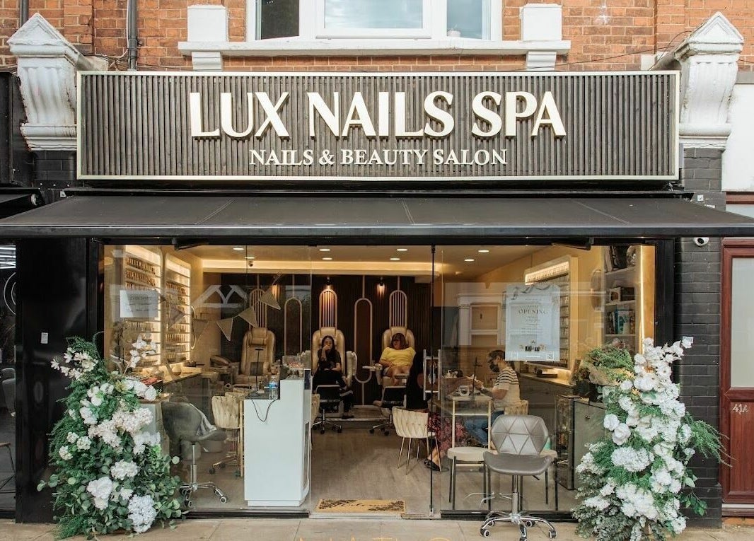 Lux Nail Spa & Beauty entrance in London, England, GB, showcasing stylish chairs and lush floral decor.