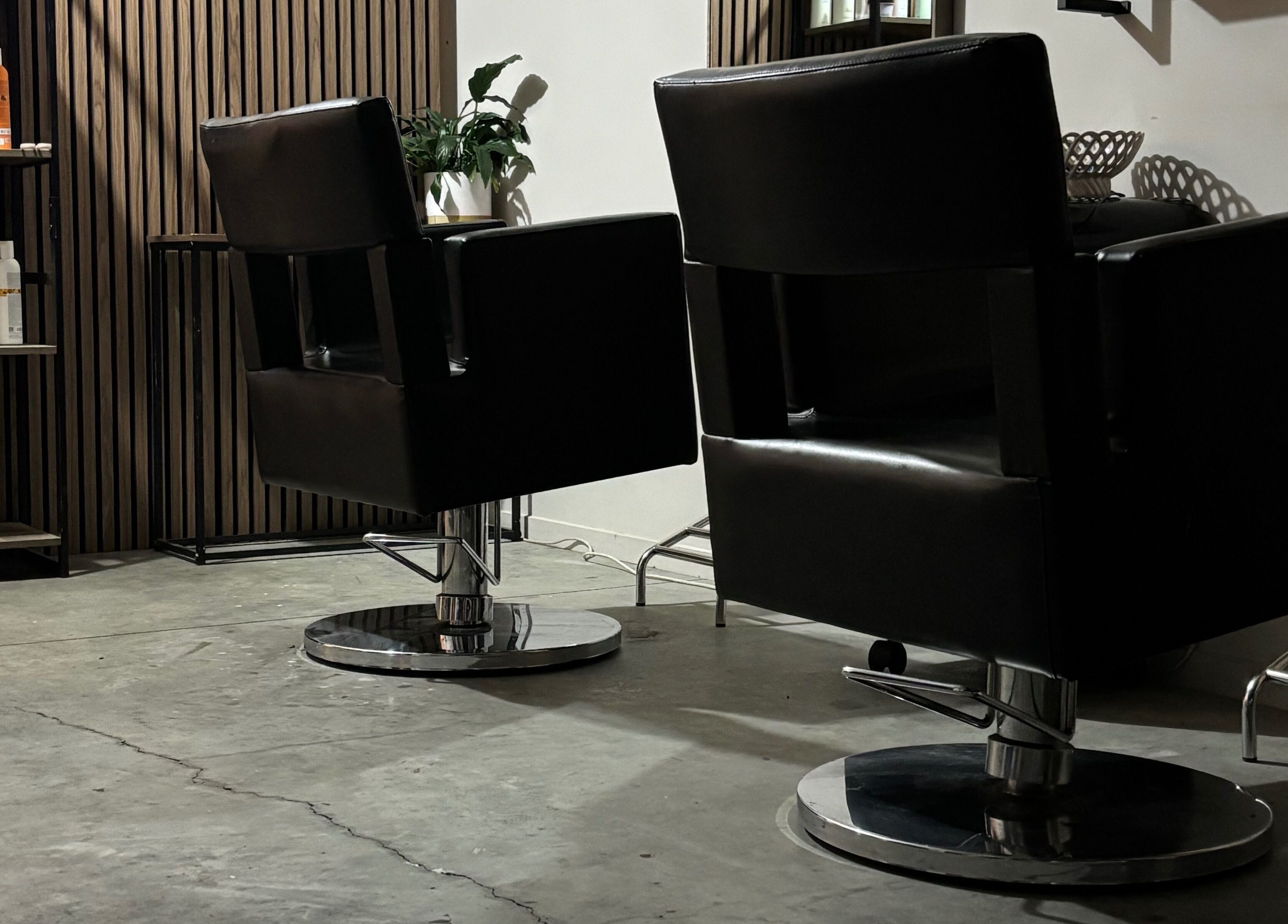 Modern salon chairs at Rah, Hastings, Hawke's Bay, NZ, alongside professional hair products on wooden shelves.