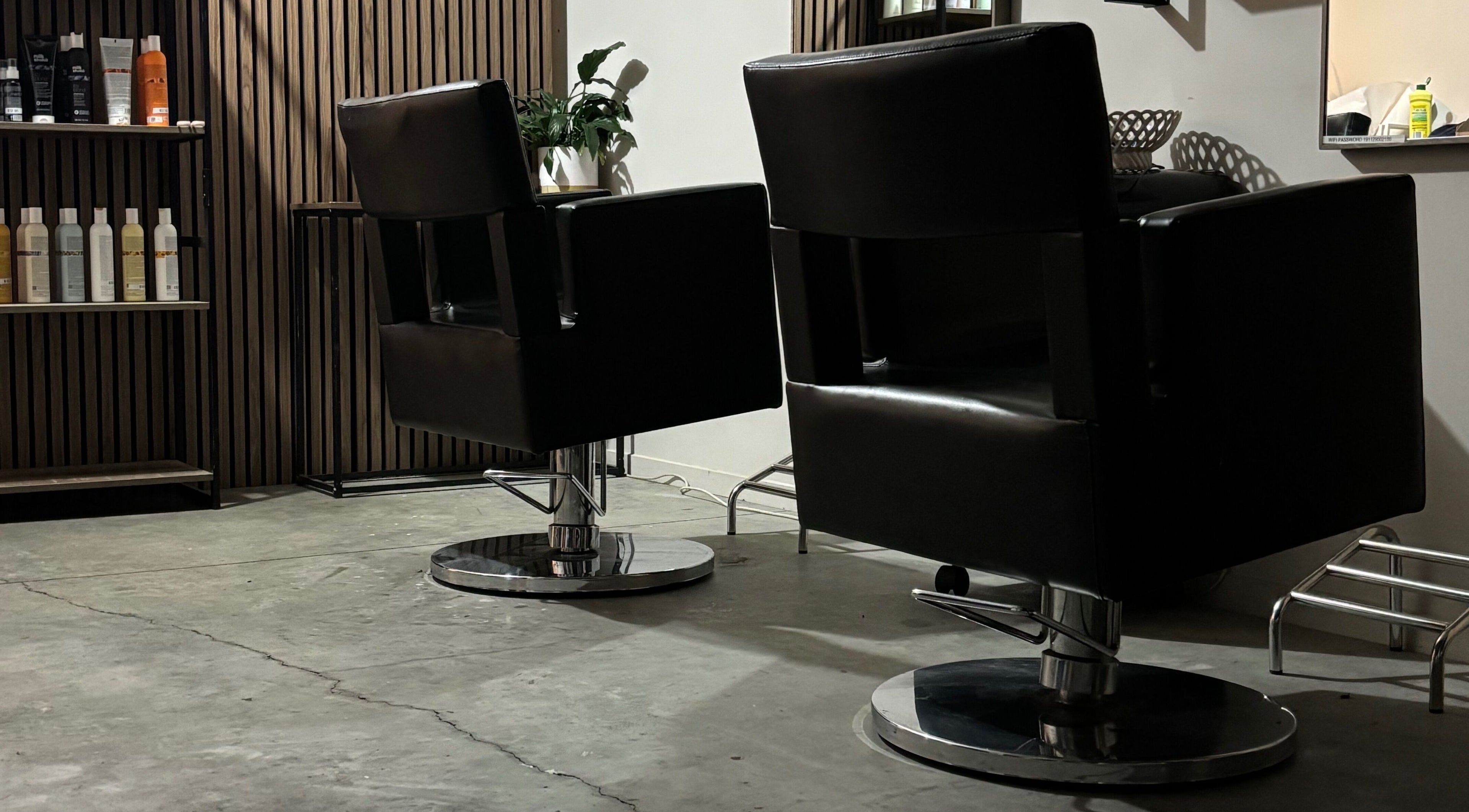 Modern salon chairs at Rah, Hastings, Hawke's Bay, NZ, alongside professional hair products on wooden shelves.