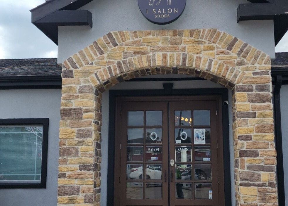 Front entrance of Ash Did That salon in Humble, Texas, US, showcasing rustic stone arch design.