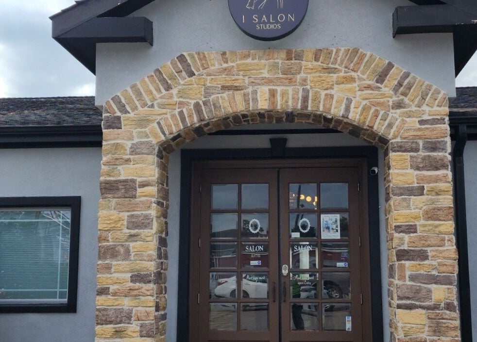Front entrance of Ash Did That salon in Humble, Texas, US, showcasing rustic stone arch design.