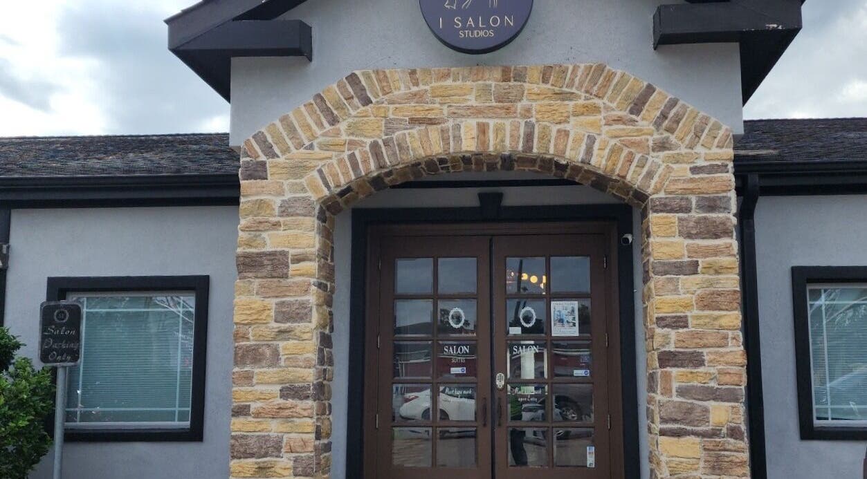 Front entrance of Ash Did That salon in Humble, Texas, US, showcasing rustic stone arch design.