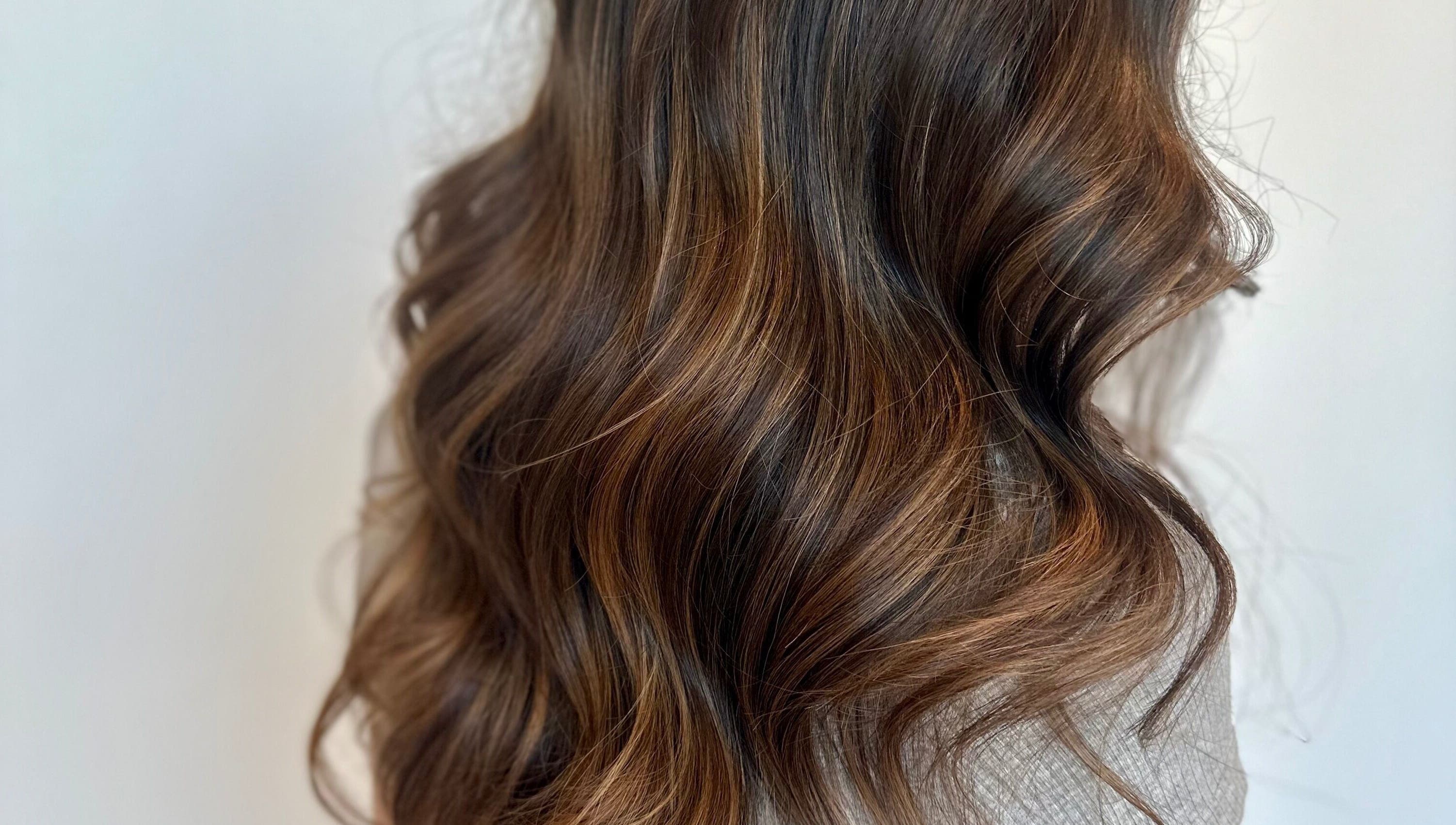 Boucles brunes impeccables à Studio Mode, Montréal, Québec, CA, mettant en valeur des tons riches.