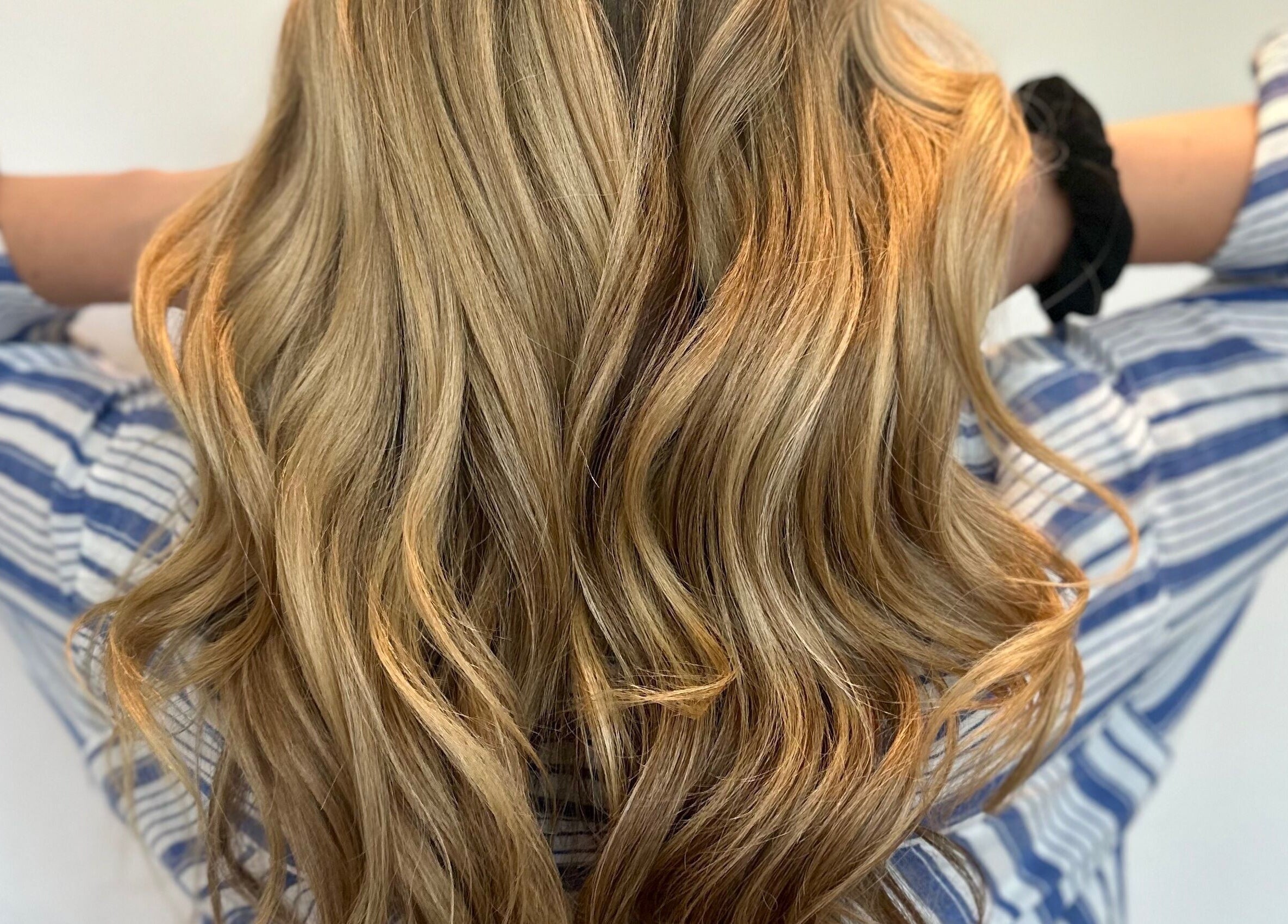 Cheveux ondulés dorés à Studio Mode, Montréal, Québec, CA, offrant des soins capillaires de qualité.