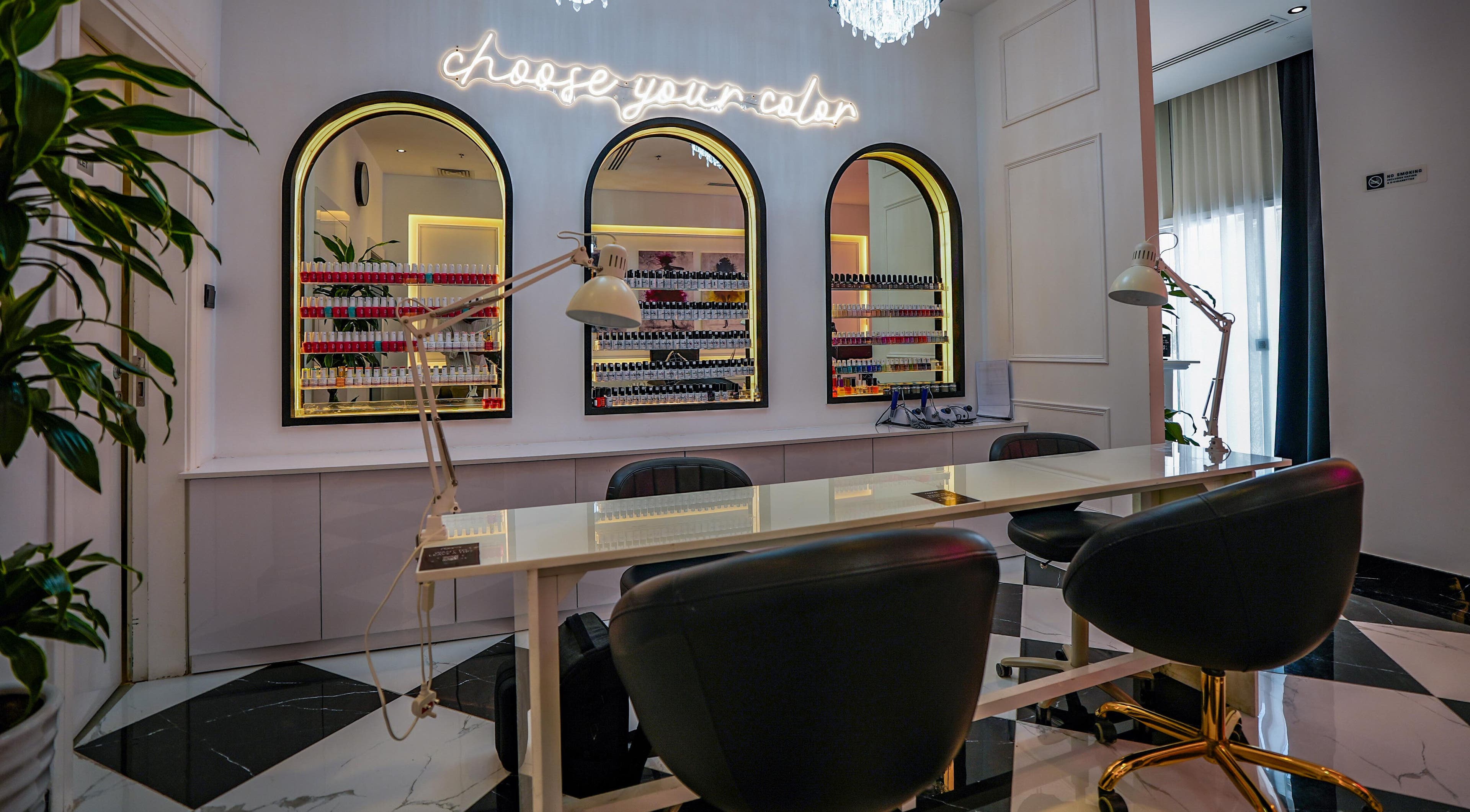 Manicure station at Noona Beauty Salon - JVC in Dubai, Dubai, AE with mirrors and nail polish display.