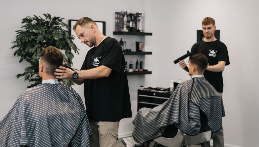 Professional barbers at MAD BARBERS in Jelgava, LV, styling clients' hair in a modern salon setting.