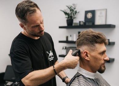 Barber expertly trims hair at MAD BARBERS, Jelgava, LV, showcasing professional grooming services.