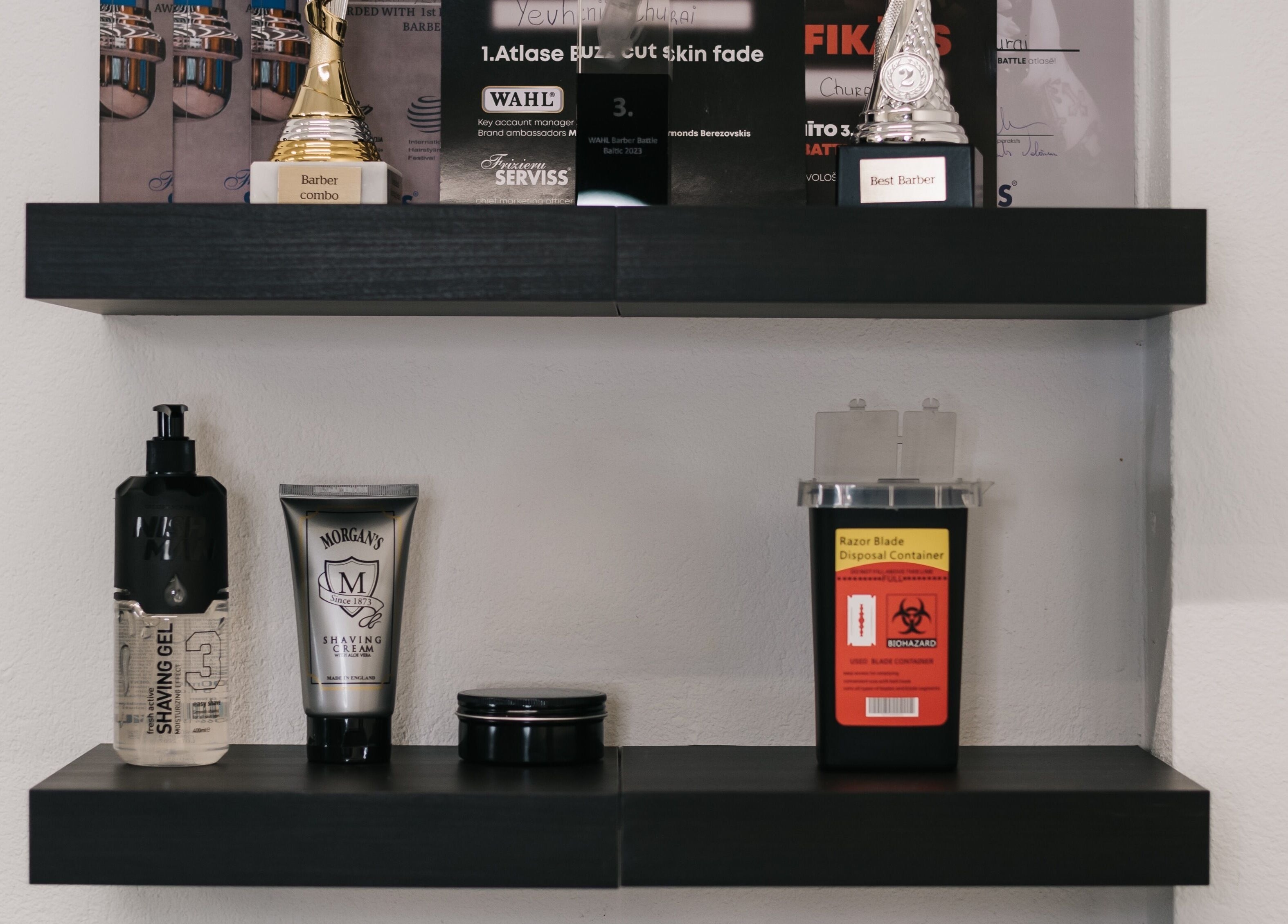 Award-winning MAD BARBERS Jelgava, LV showcase with trophies and grooming products on shelves.