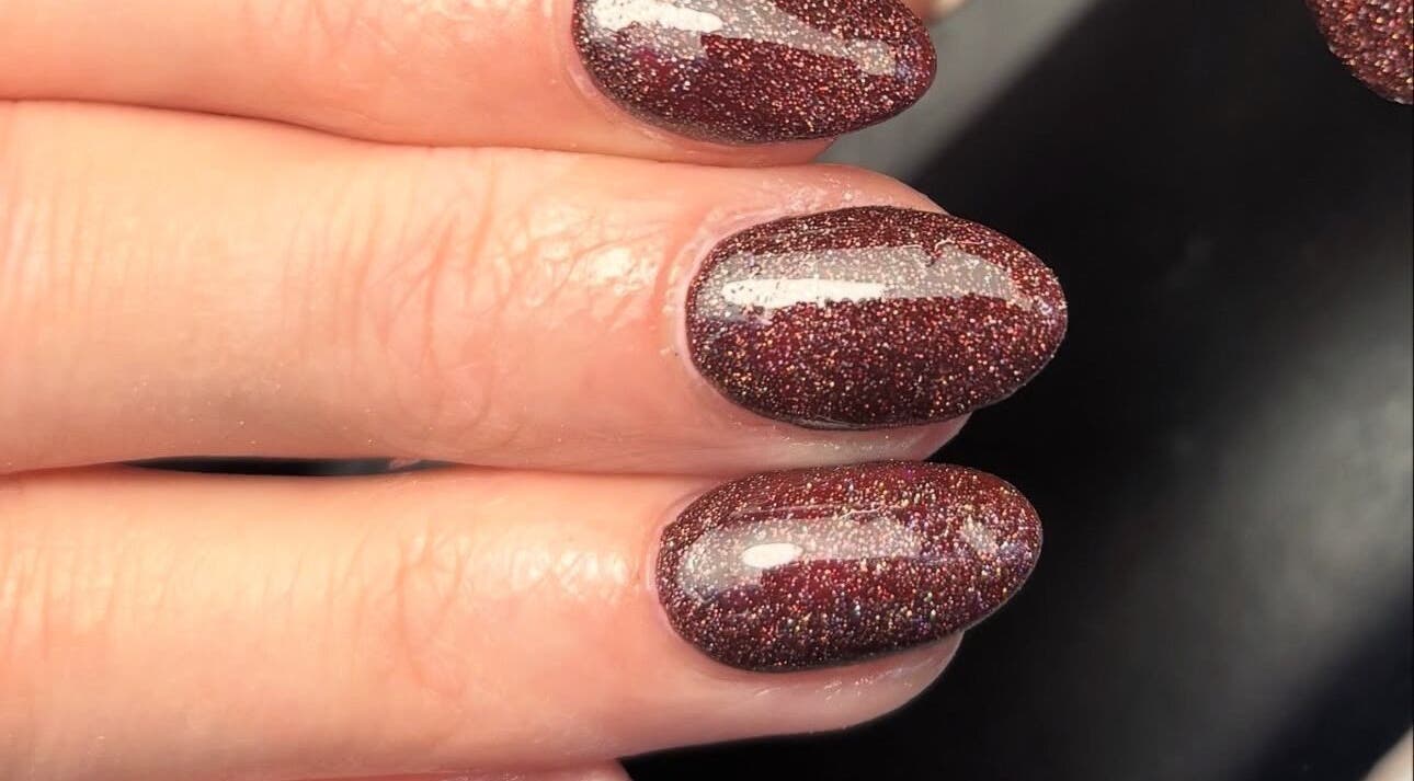 Elegant glittery manicure at Juicy Beauty, Gateshead, England, GB showcasing maroon sparkly nails.