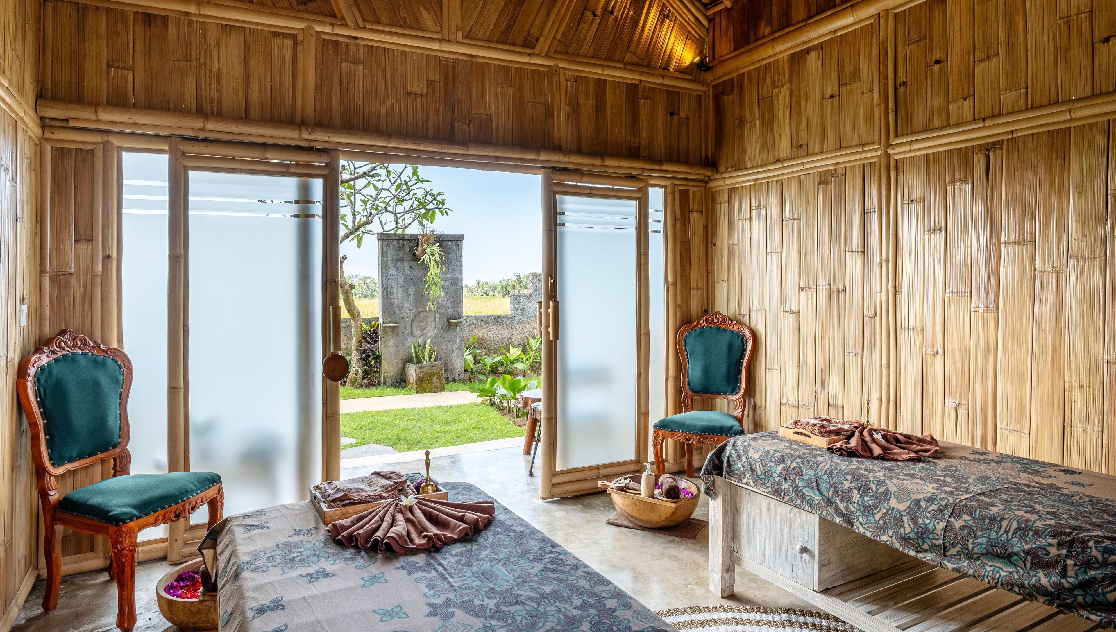 Elegant bamboo interior of Visesa Spa in Bali, Bali, ID, featuring massage tables and ornate chairs.