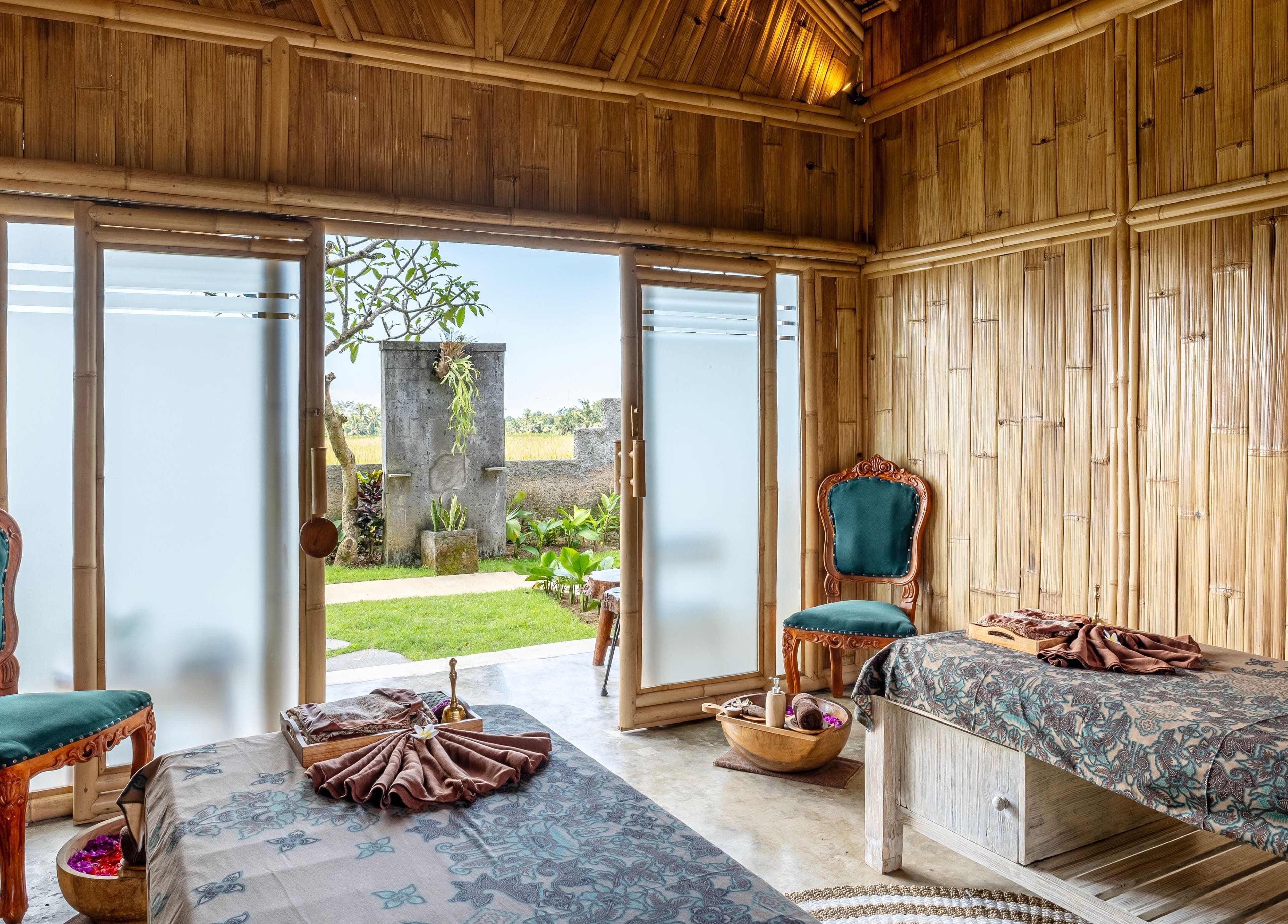 Elegant bamboo interior of Visesa Spa in Bali, Bali, ID, featuring massage tables and ornate chairs.