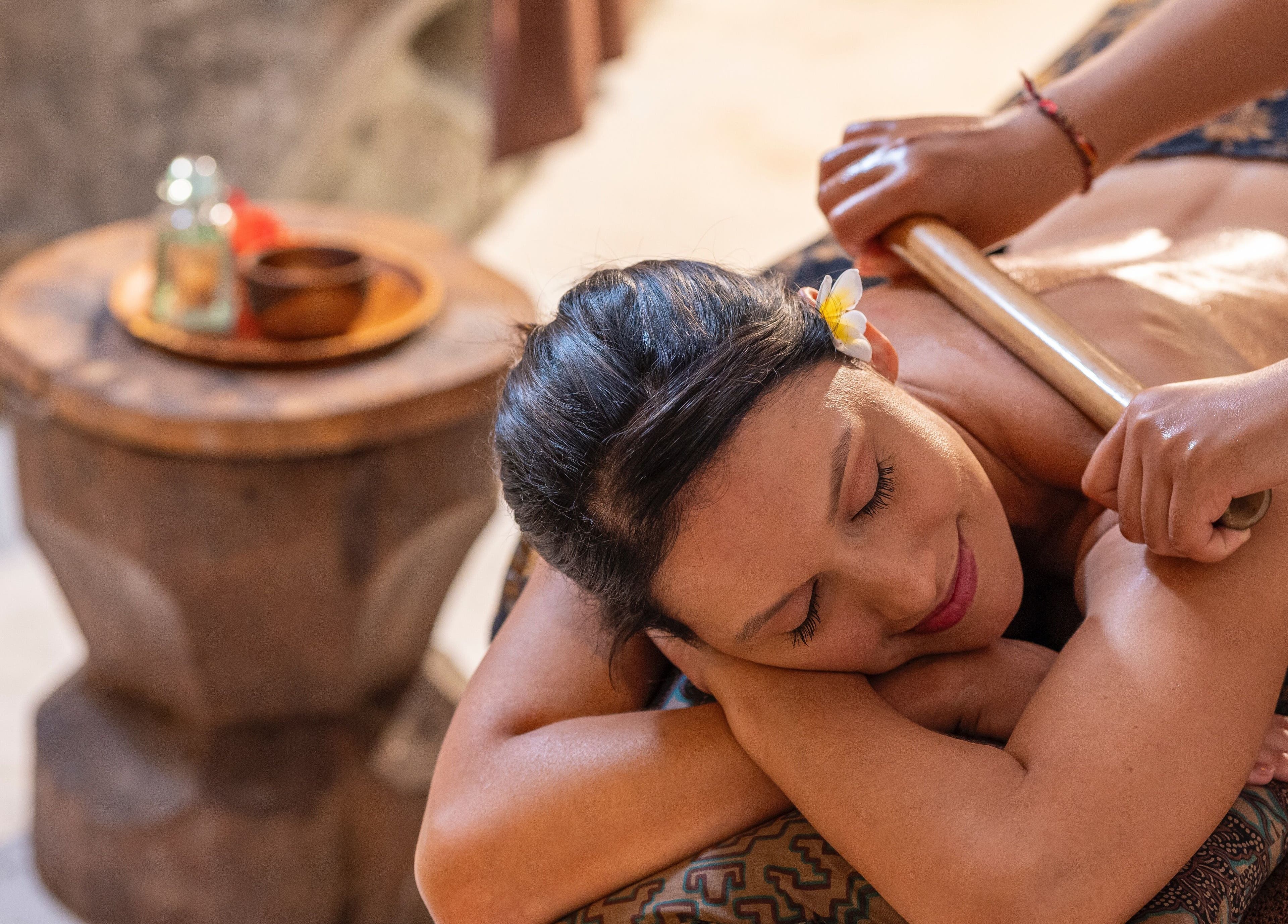 Woman enjoying a soothing massage at Visesa Spa, Bali, Bali, ID, surrounded by serene ambiance and natural decor.