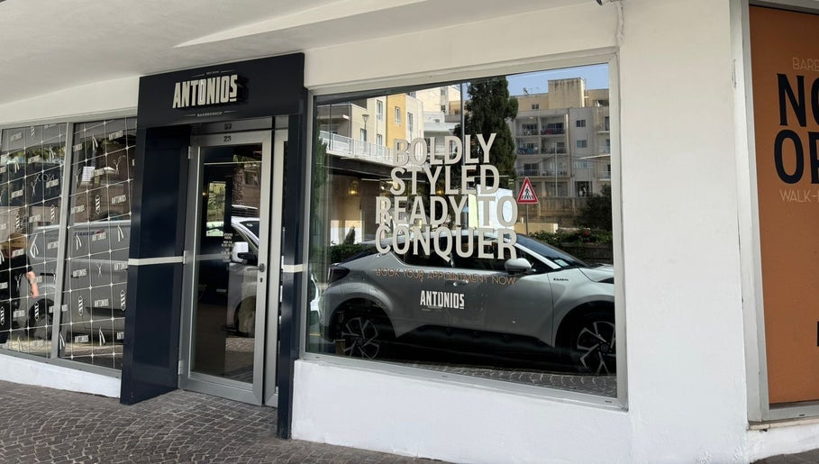 Entrance of Antonio's Barbershop Spinola Park, San Ġiljan, MT with stylish storefront and bold signage.