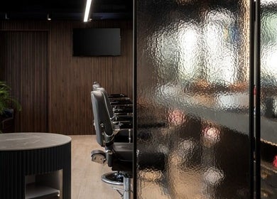 Modern interior of Antonio's Barbershop Spinola Park, San Ġiljan, MT with sleek chairs and wood panel design.