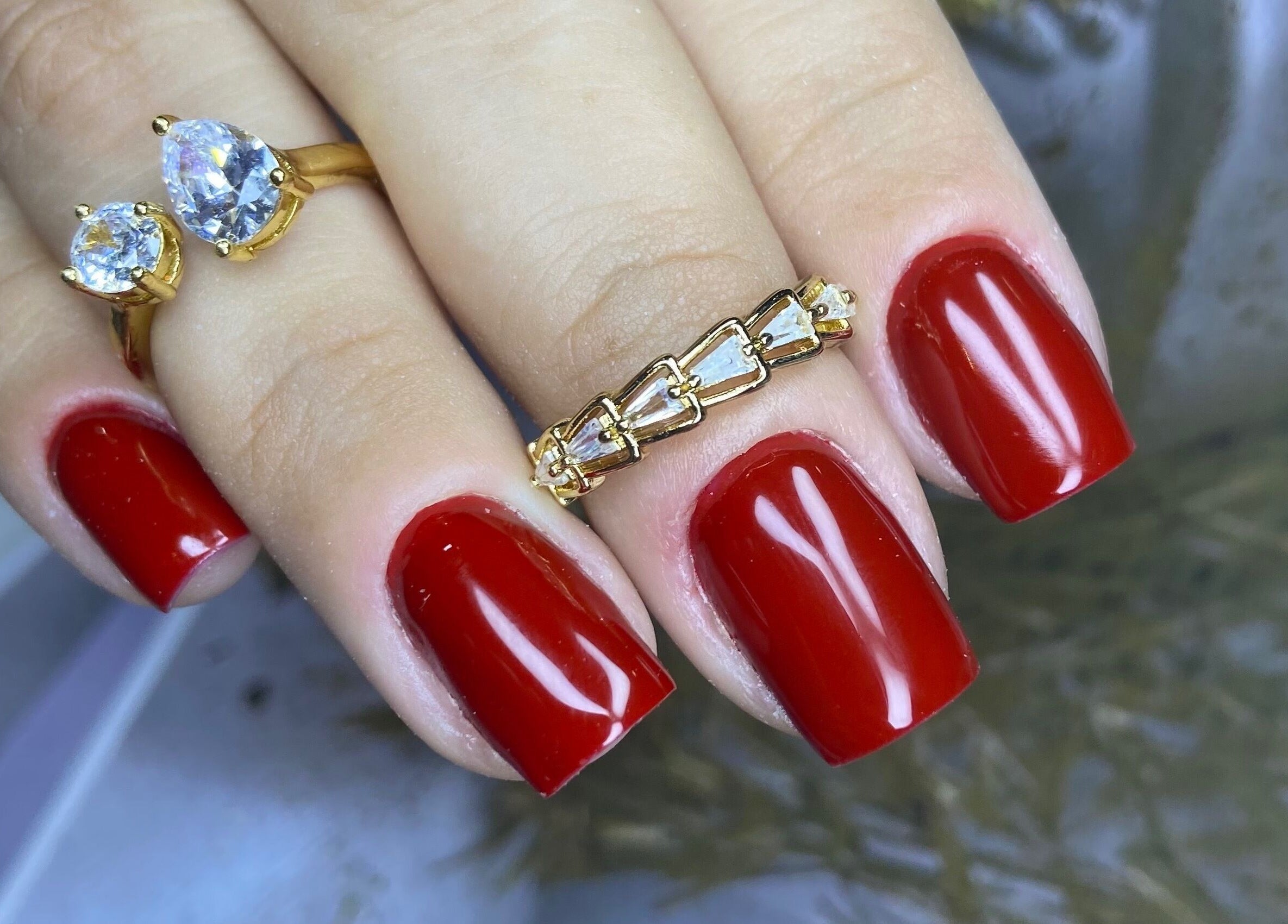 Unhas vermelhas elegantes com anéis de luxo no Studio Carol Florez, São Paulo.