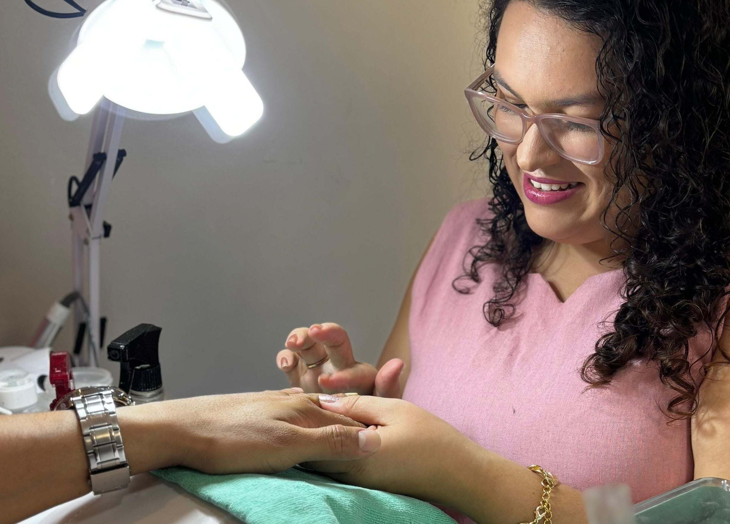 Profissional sorrindo realiza manicure no Studio Carol Florez, São Paulo, São Paulo, BR.
