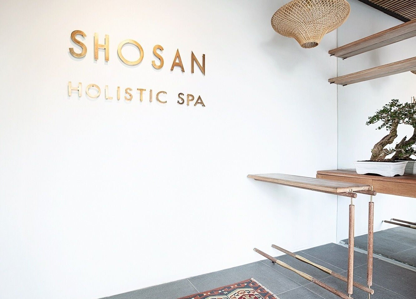 Entrance of Shosan Holistic Spa, Bali, with minimalist decor and bonsai tree.