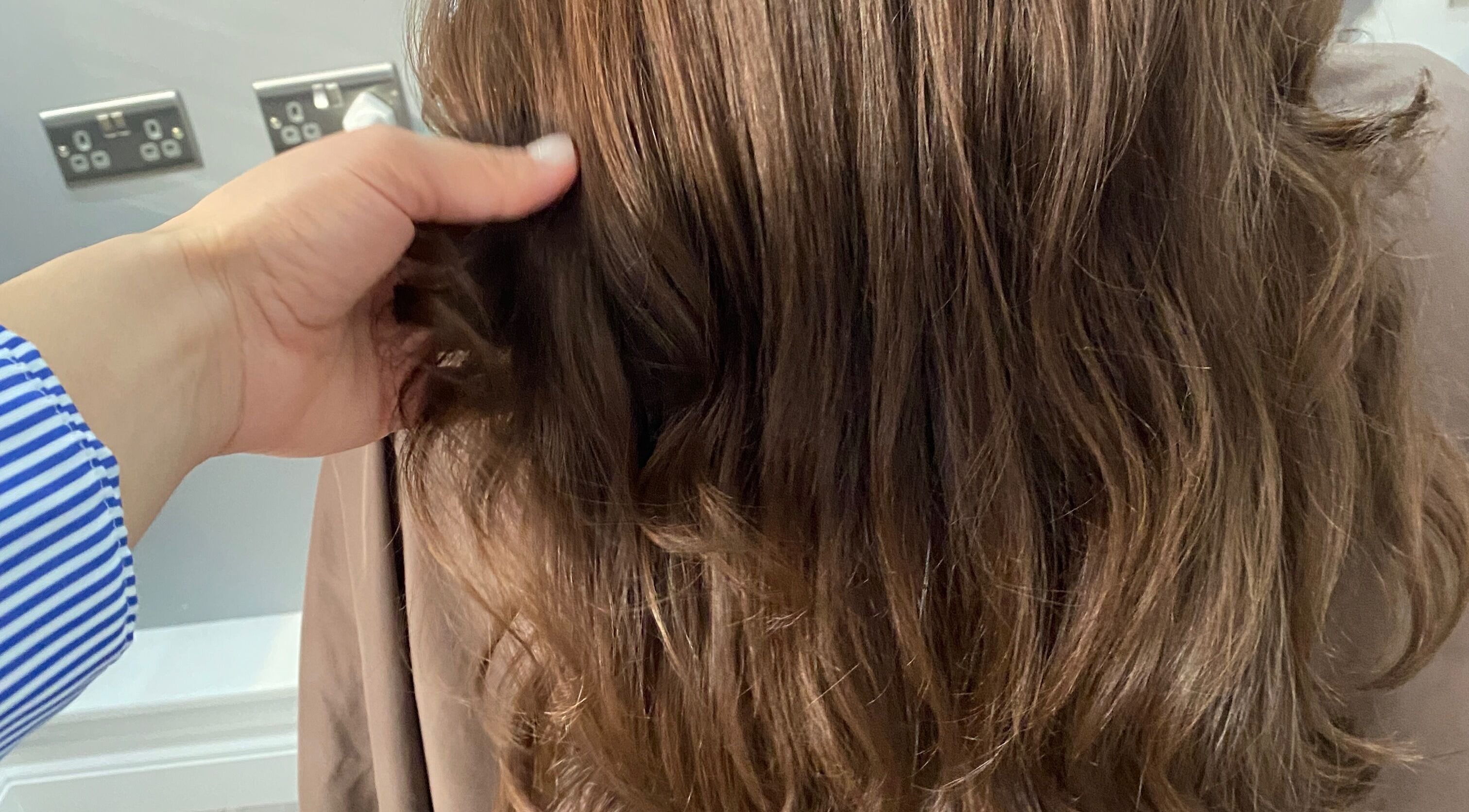 Stylish brown wavy hair being styled at HairMatters by Mariana in Feltham, England, GB.
