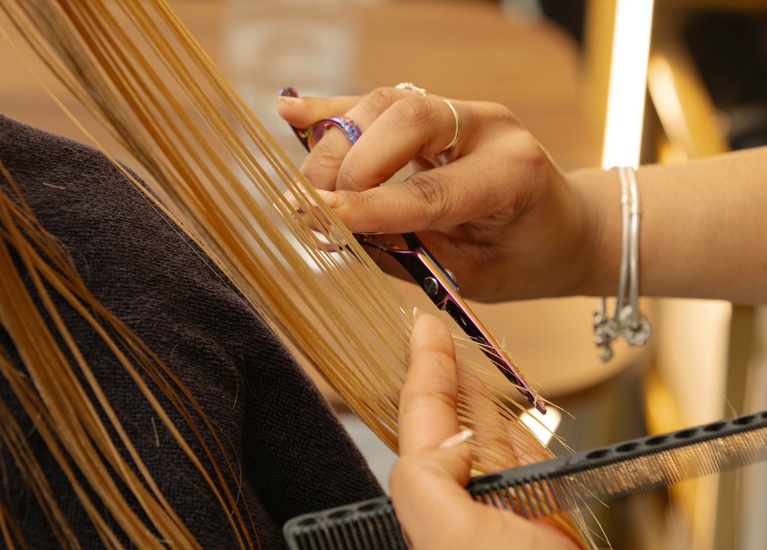 Stylist cutting hair with precision at About YU, London, England, GB. Enhance your look today.