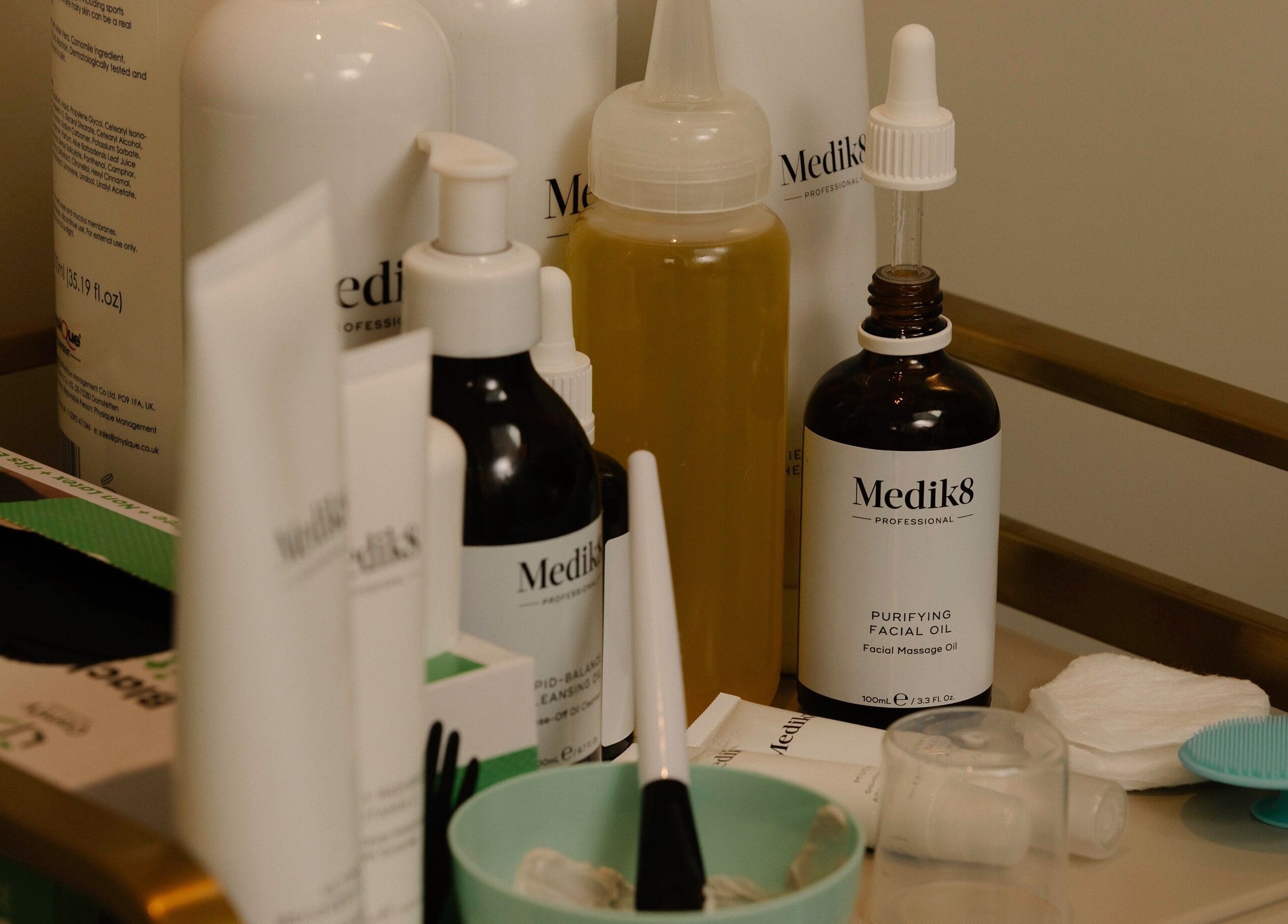 Assortment of skincare products and tools at About YU, London, England, GB, on a treatment counter.