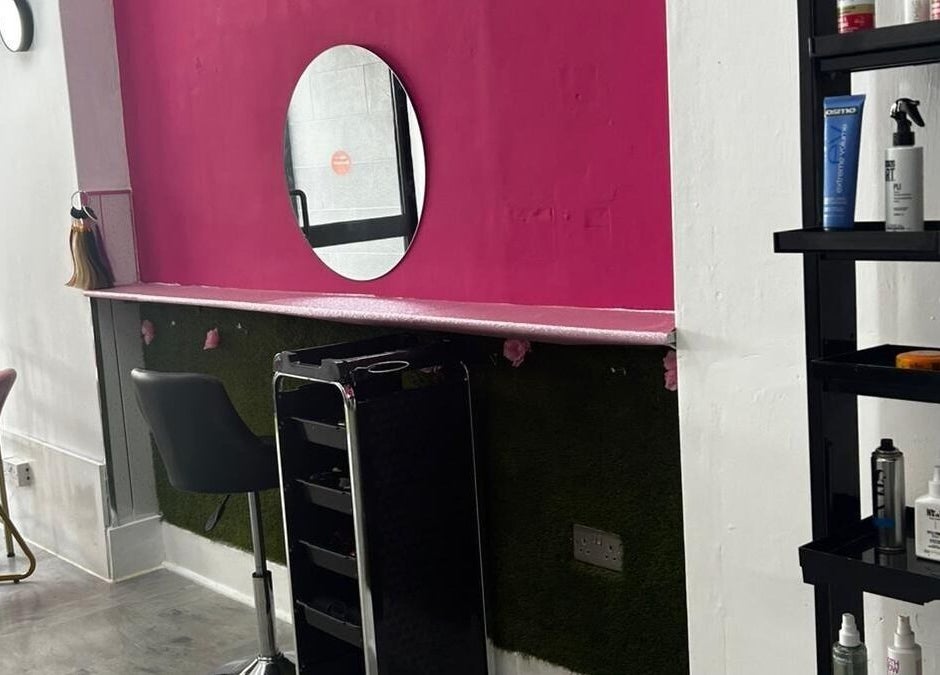 Stylish workstation at Elegant Styles Studio, Glasgow, Scotland, GB, featuring vibrant pink walls and sleek furniture.