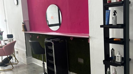 Stylish workstation at Elegant Styles Studio, Glasgow, Scotland, GB, featuring vibrant pink walls and sleek furniture.