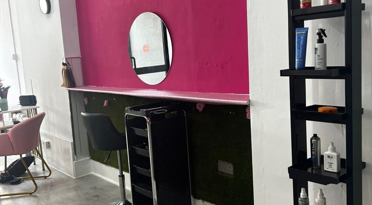 Stylish workstation at Elegant Styles Studio, Glasgow, Scotland, GB, featuring vibrant pink walls and sleek furniture.