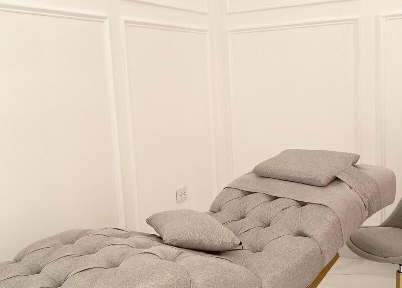 Sala de tratamiento en Althea Beauty Bar, Durango, Durango, MX, con silla gris y camilla cómoda.
