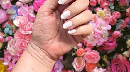 Elegant white manicure against vibrant flowers at Nadine's Nail&Beauty Bar Techno Park Stellenbosch, Western Cape, ZA.