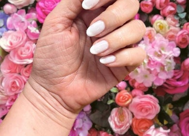 Elegant manicured nails set against a vibrant floral background at Nadine's Nail & Beauty Bar Techno Park Stellenbosch.