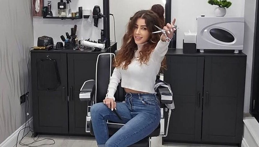Hair stylist at Sabi Style salon, Edgware, England, GB, holding scissors in chic salon setting.