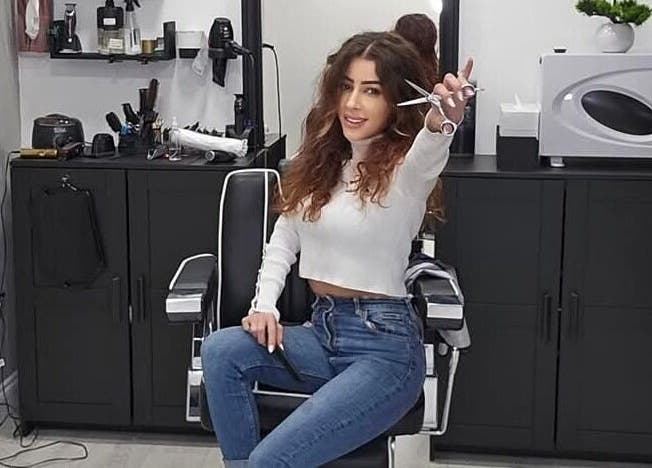 Hair stylist at Sabi Style salon, Edgware, England, GB, holding scissors in chic salon setting.