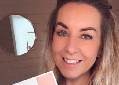 Smiling stylist at Jayme’s Home Studio, Hornchurch, England, GB, displaying makeup palette.