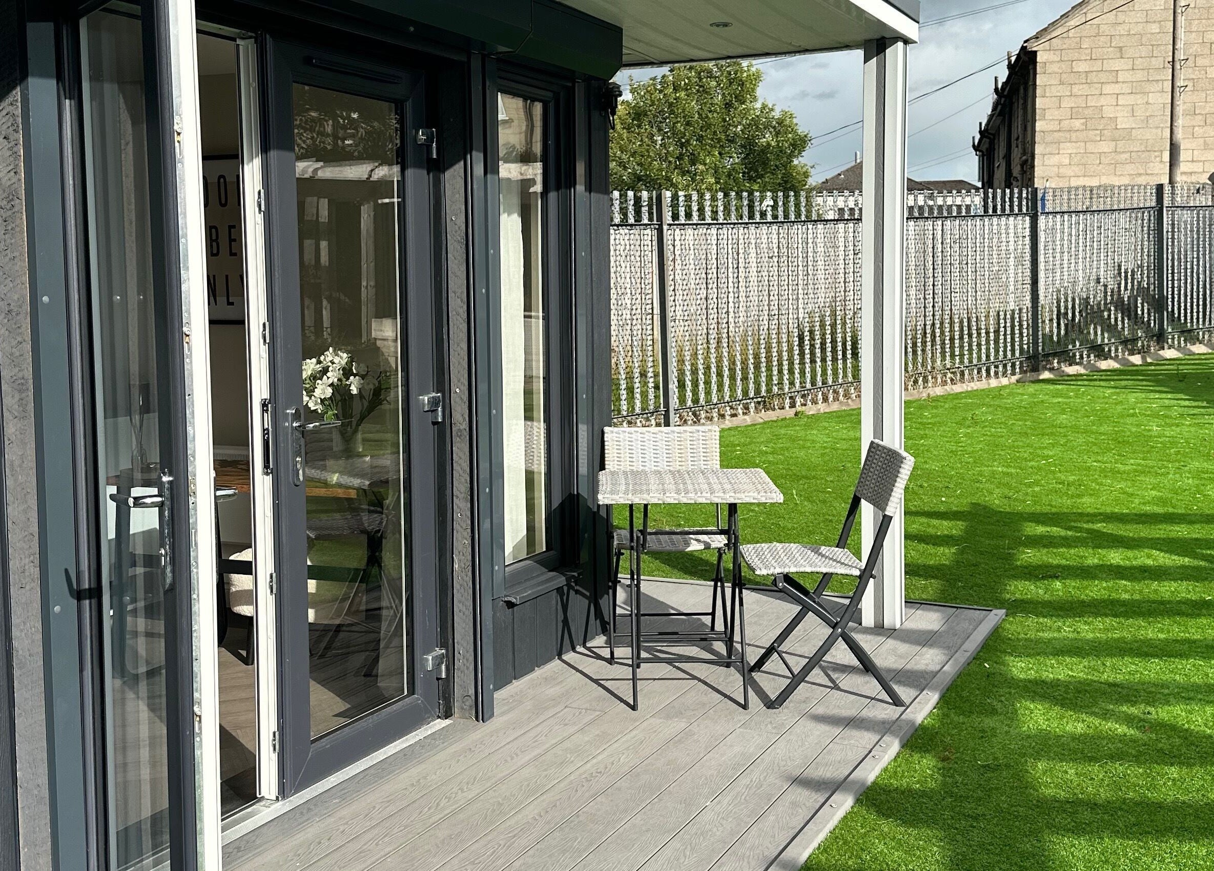 Outdoor patio at Soul Skin Studio and Wellness, Blantyre, GB, featuring a table and chairs on lush green grass.