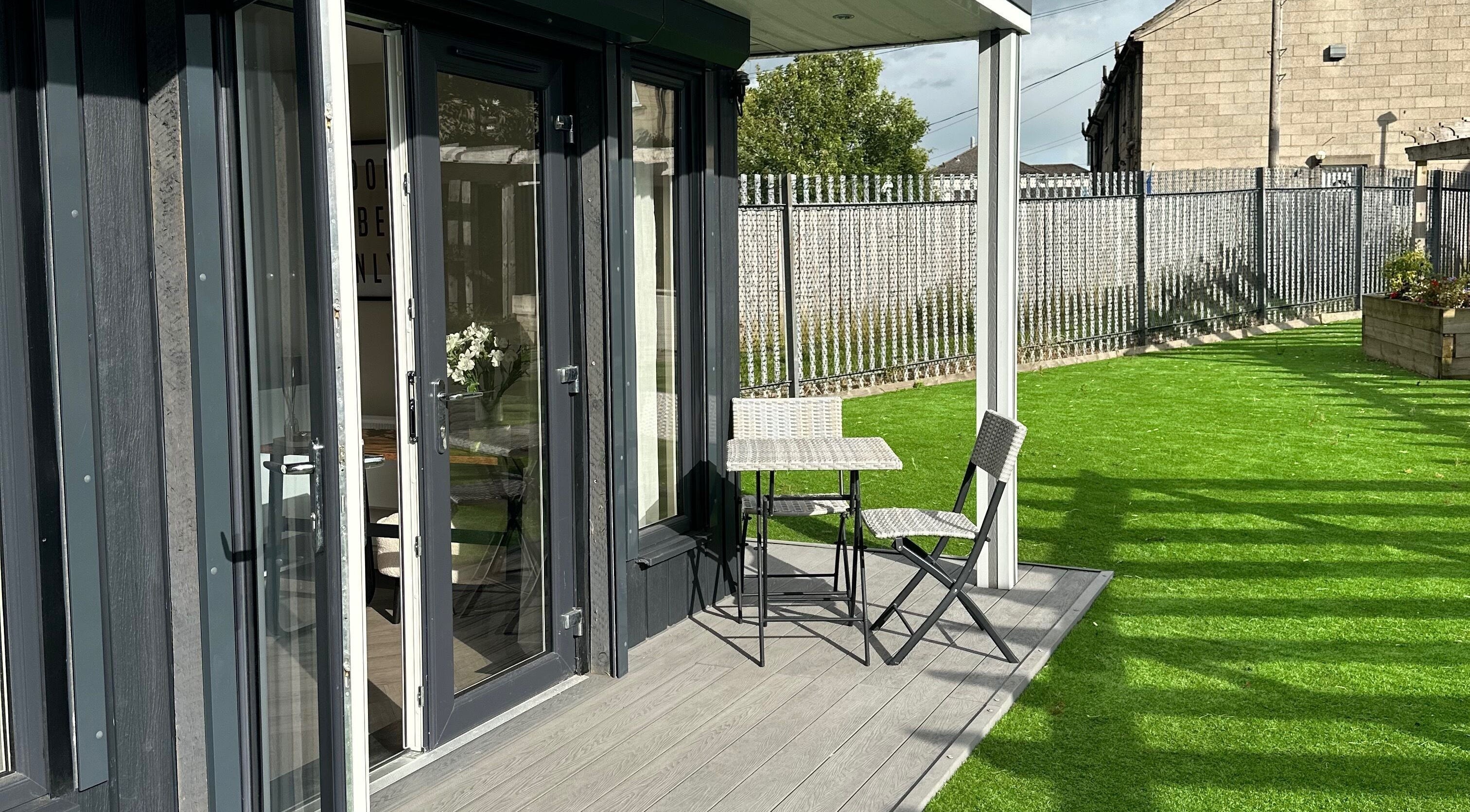 Outdoor patio at Soul Skin Studio and Wellness, Blantyre, GB, featuring a table and chairs on lush green grass.