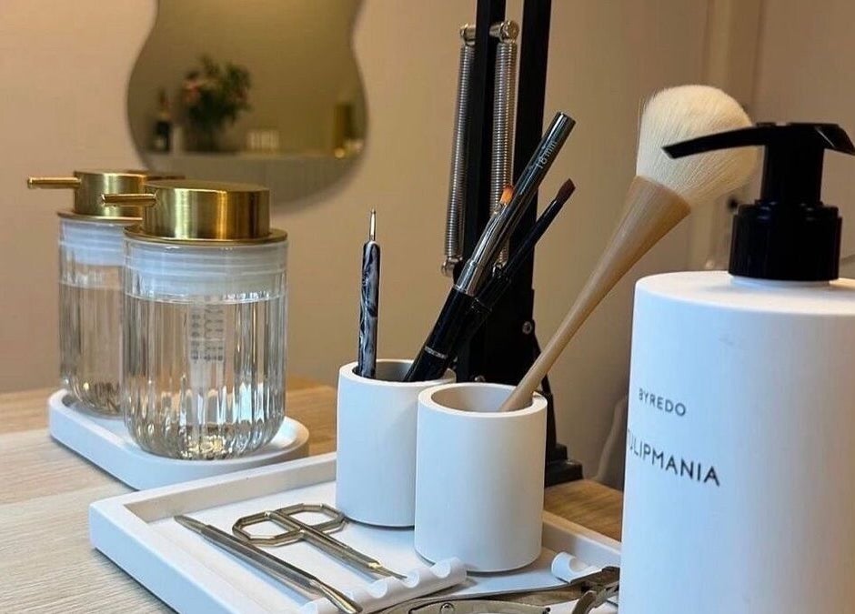 Mesa de herramientas de belleza en Blue Studio, Maracaibo, Zulia, VE, con dispensadores elegantes y pinceles de maquillaje.