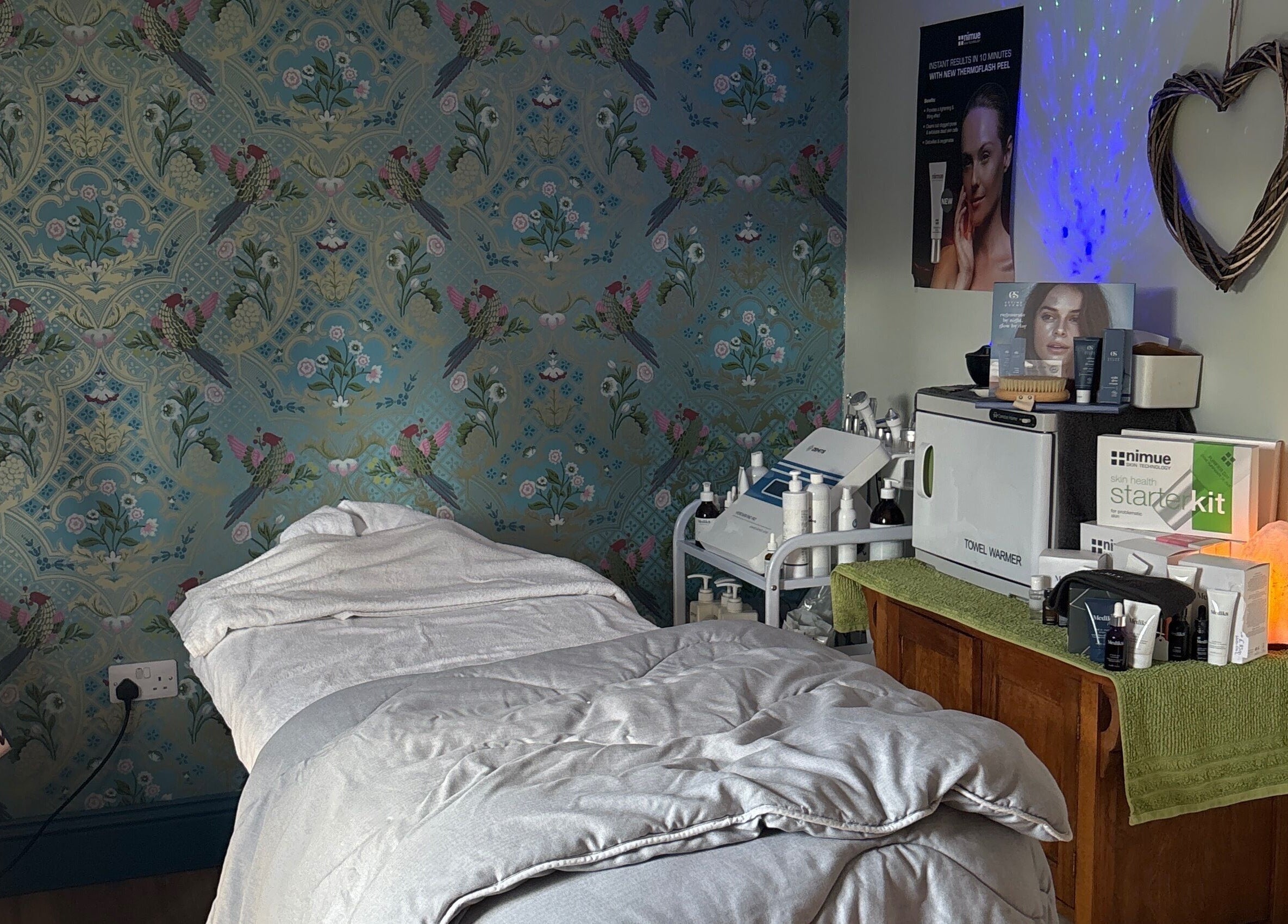 Serene treatment room at The Beauty Hideout, Goosnargh, England, featuring cozy bed and skincare products.