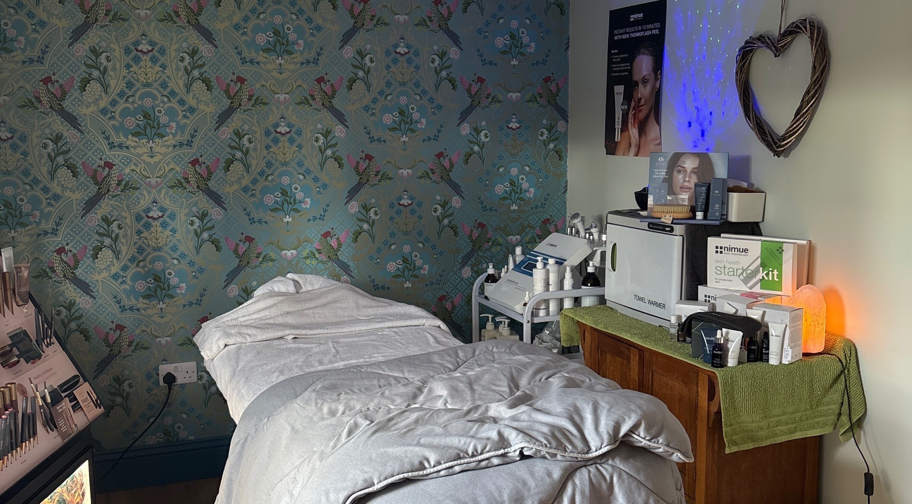 Serene treatment room at The Beauty Hideout, Goosnargh, England, featuring cozy bed and skincare products.