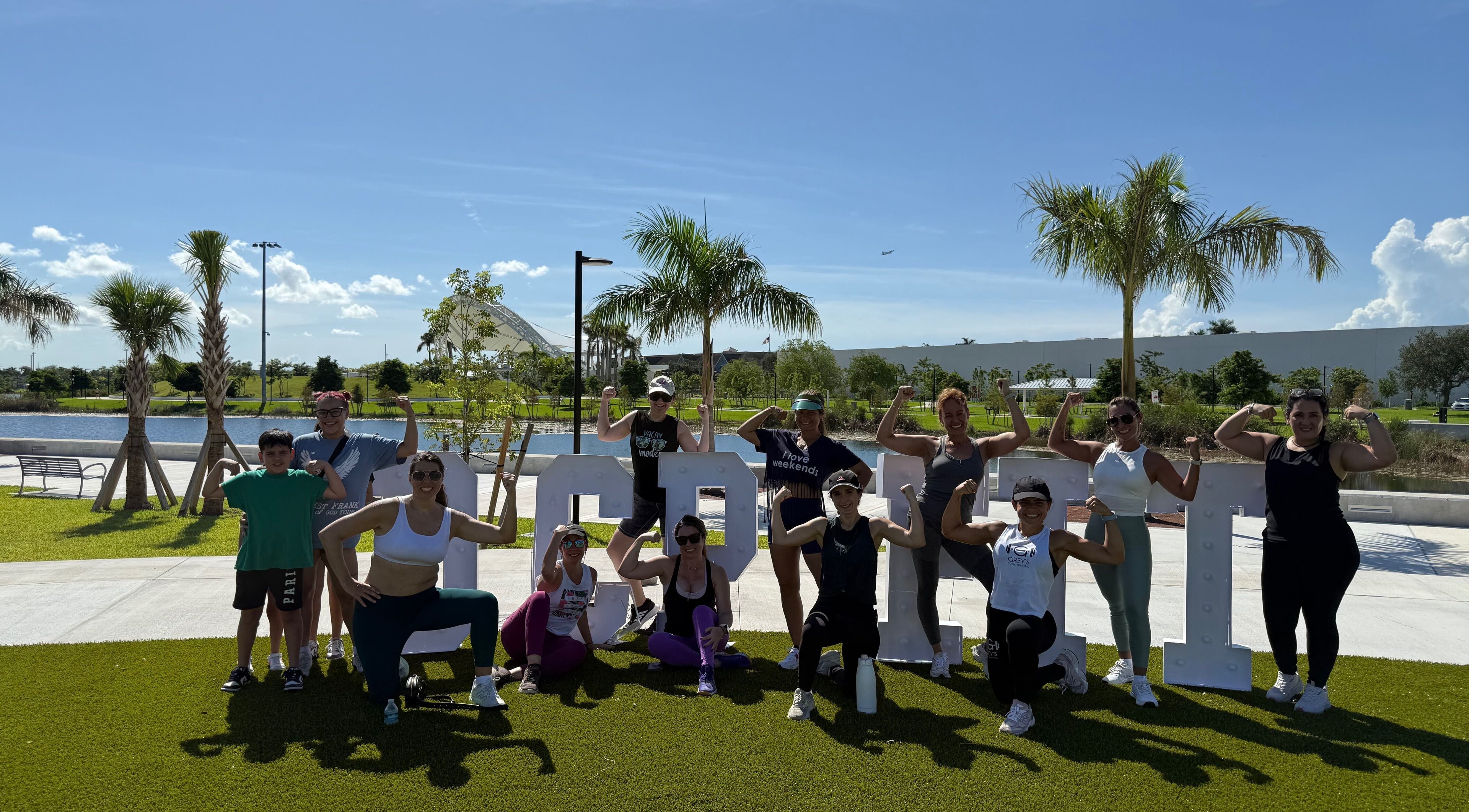 Group fitness session at Grey’s Total Training, Miami, Florida, US. Participants flexing muscles and enjoying the outdoors.