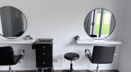 Two styling stations at Malimou, Endeavour Hills, Victoria, AU, with round mirrors and sleek black chairs.