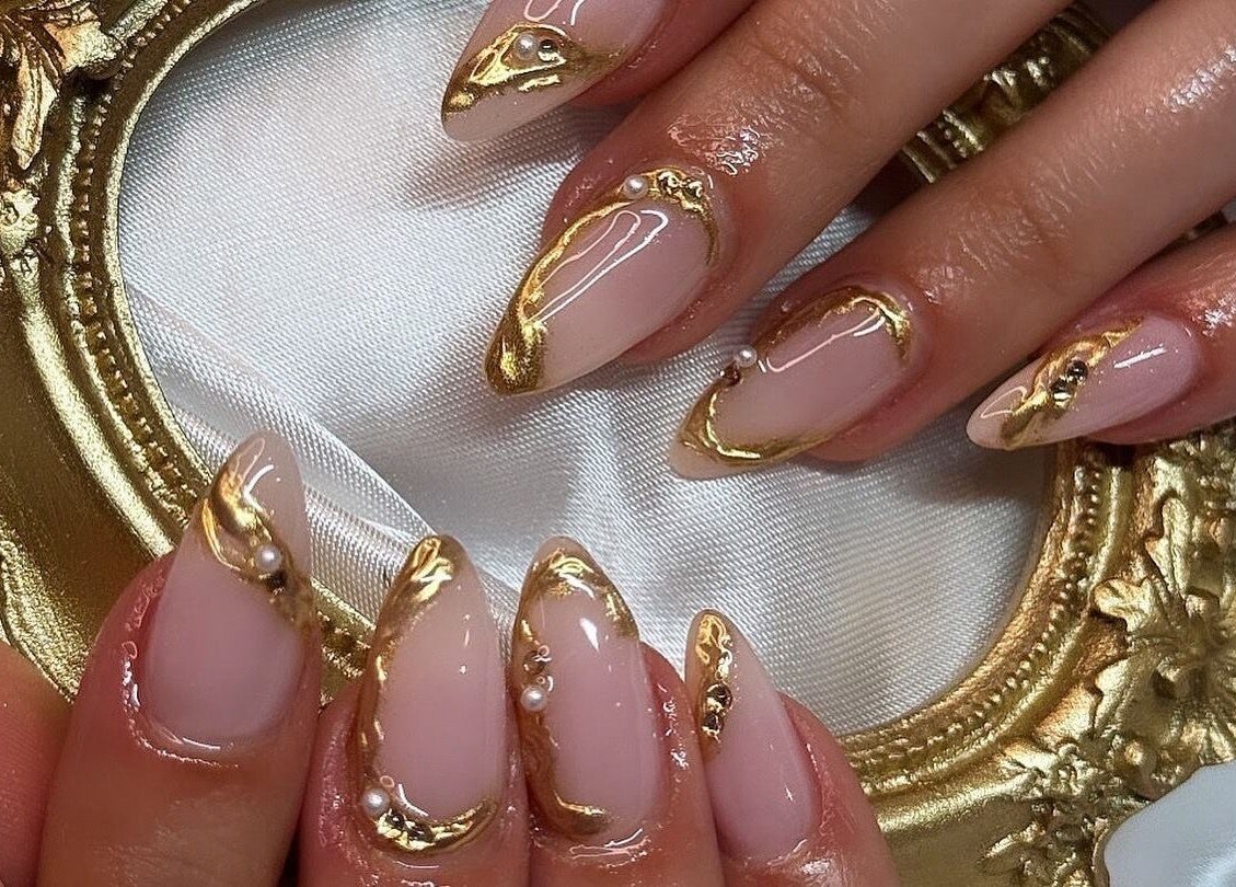 Intricate gold nail art at Beauty By Kristina Fa, Yagoona, New South Wales, AU on a delicate lace backdrop.