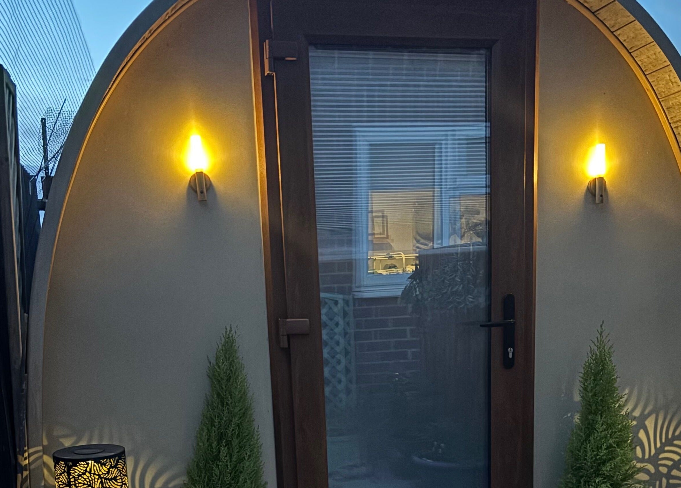 Warmly lit entrance of Rhilax pod, Ilkeston, England, GB offering a serene wellness retreat.