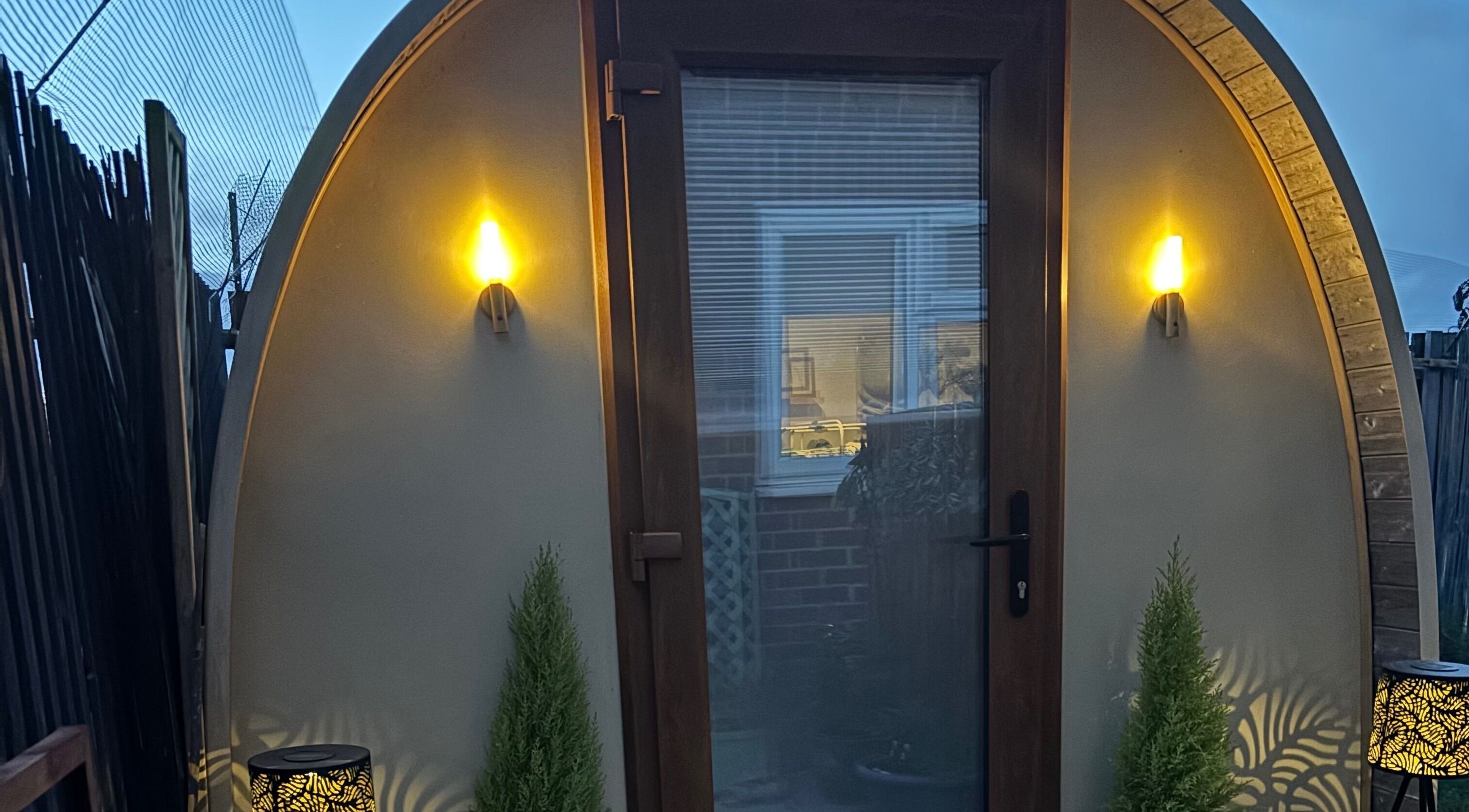 Warmly lit entrance of Rhilax pod, Ilkeston, England, GB offering a serene wellness retreat.
