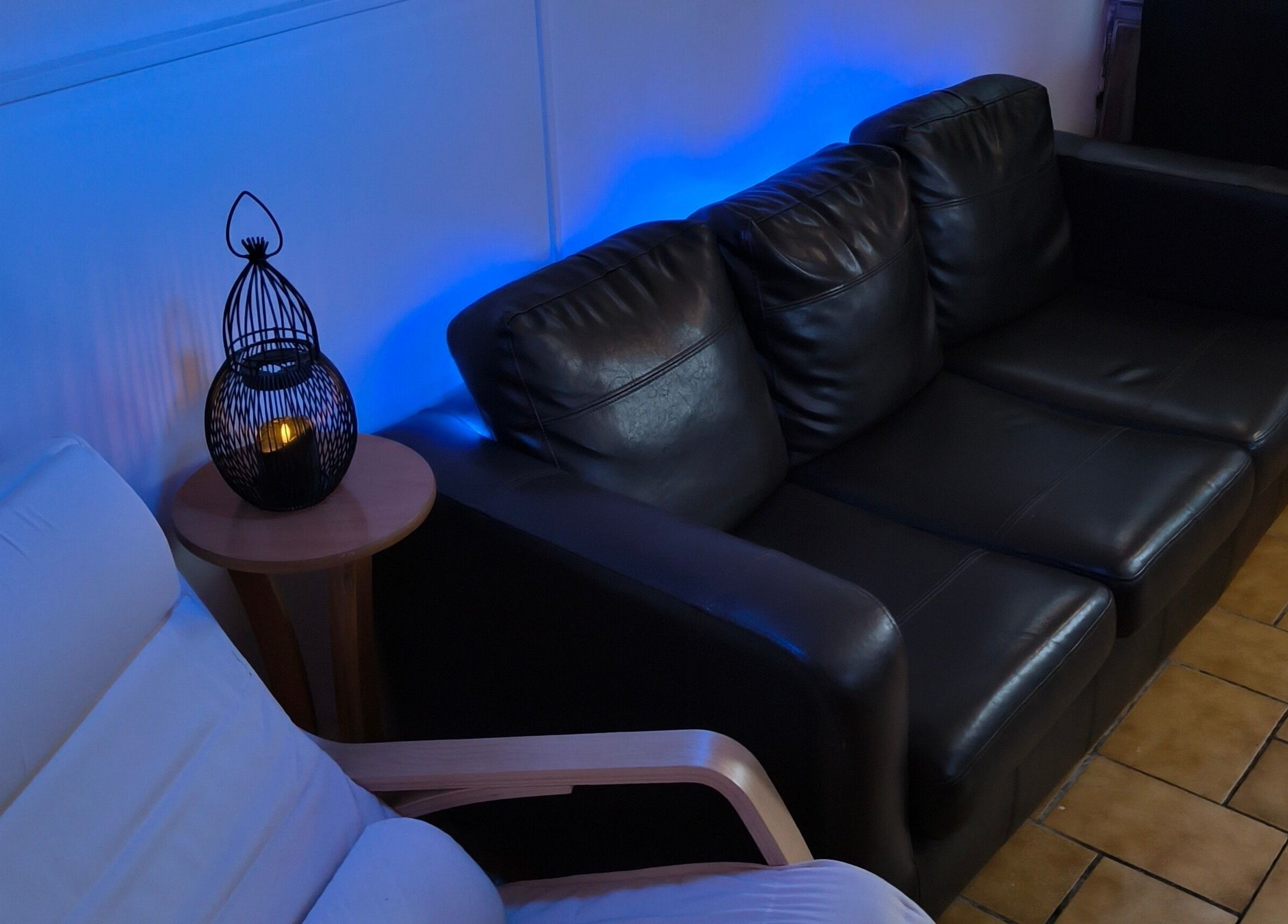 Espace détente avec canapé en cuir noir chez Le Salon De Gaïa, Ducey-les-chéris, Normandie, FR.